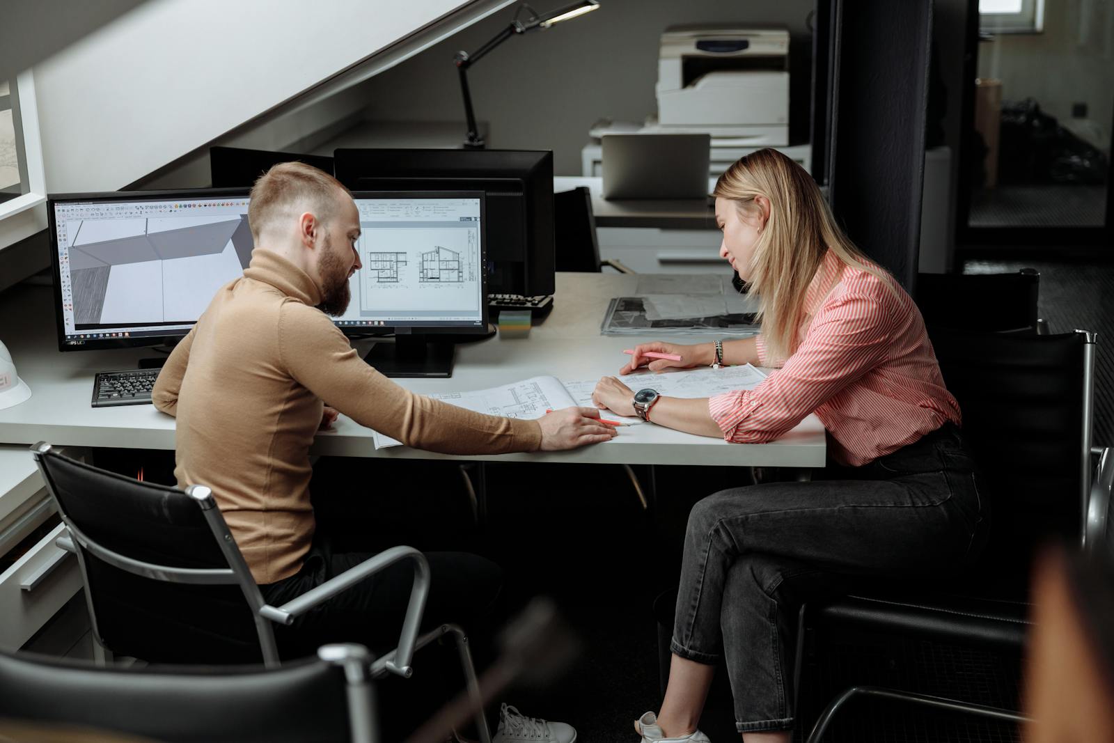 business, two architects discuss plans in a contemporary office, focusing on project details.